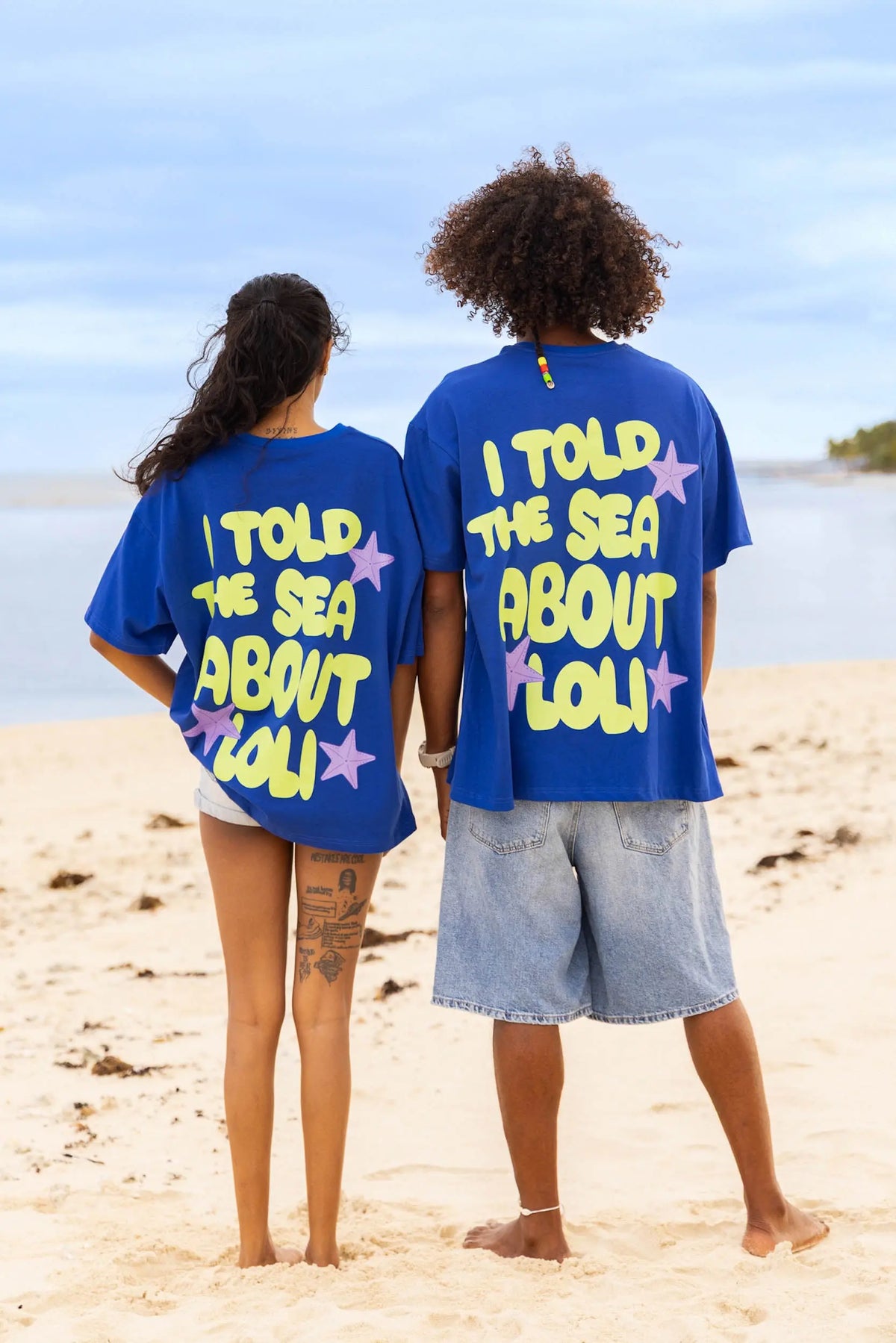 Femme et homme de dos portant le t-shirt bleu en coton Loli Seaside avec gros imprimé coloré 