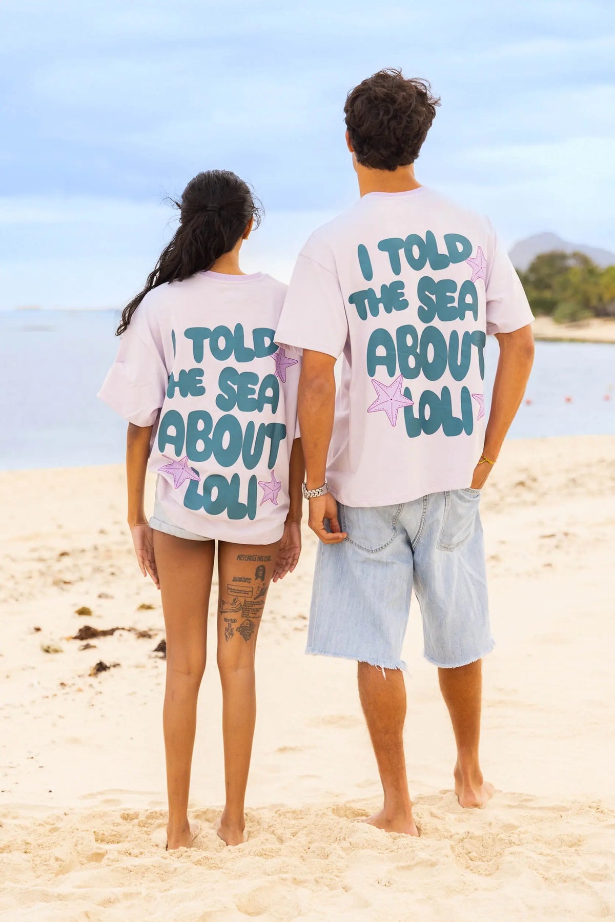 Femme et homme de dos portant le t-shirt lila Loli Seaside avec gros imprimé