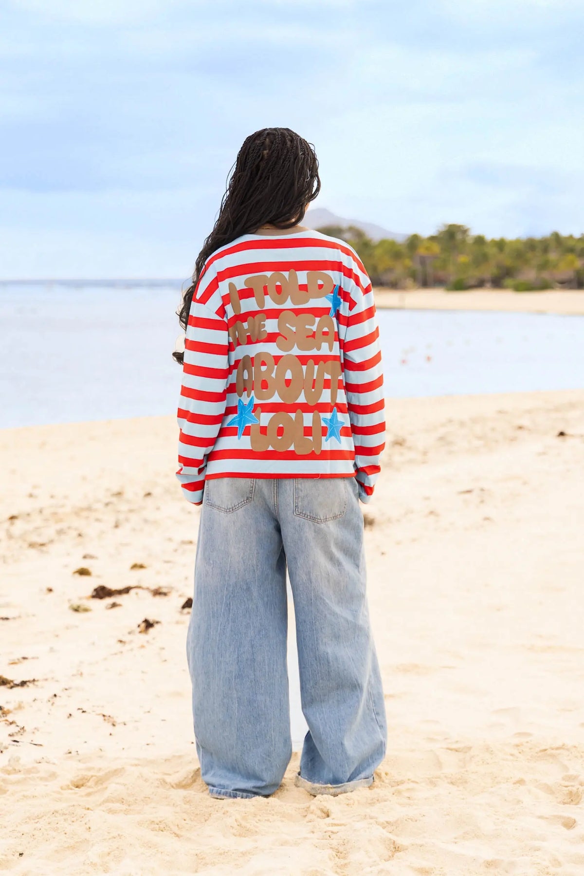 Femme de dos portant le haut oversize rayé rouge et bleu de la collection Loli Seaside avec design dans le dos 